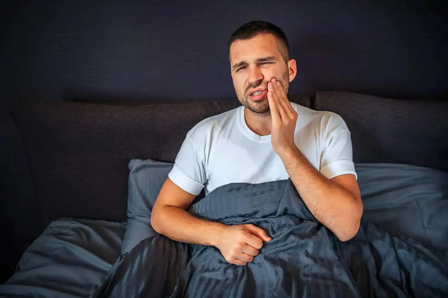 Picture of man in bed suffering from toothache.